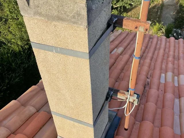 Reconstruction d'une souche de cheminée en cours, enduit fraîchement appliqué sur toiture en tuiles canal, Artisan JP